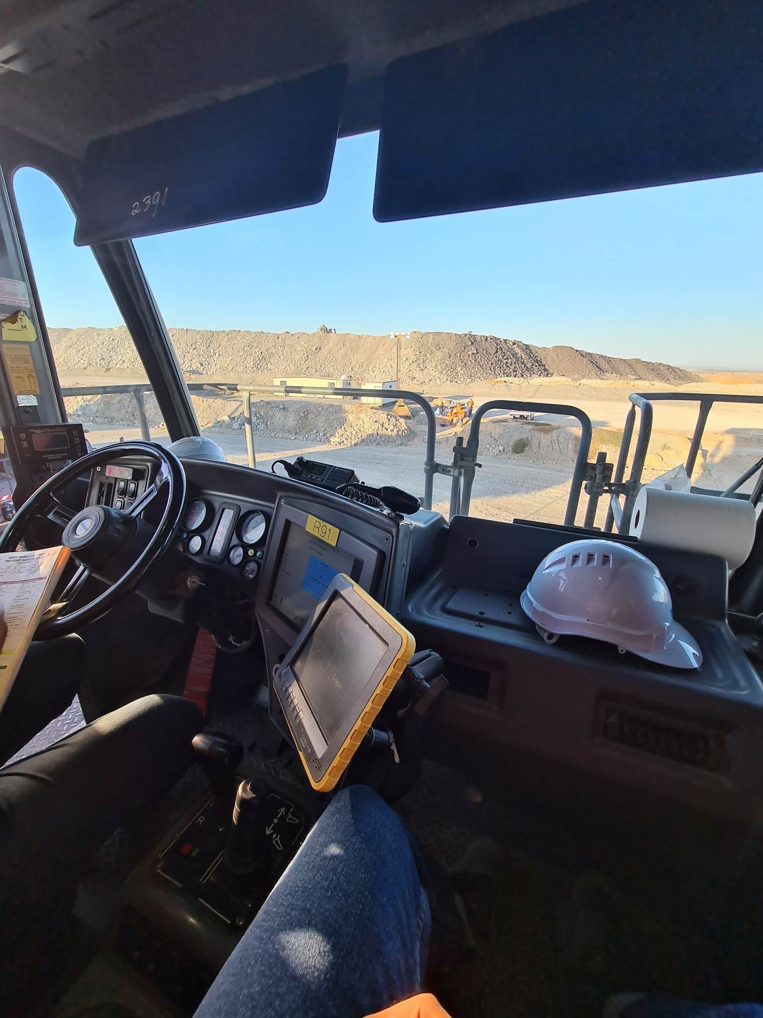 View from the cab of a haul truck on a mine site, pre-start inspection sheet in hand